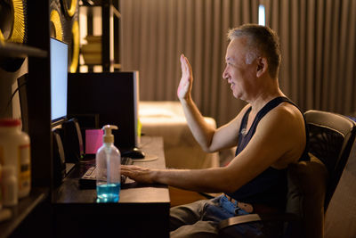 Side view of man sitting on table at home