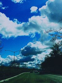 Trees on field against cloudy sky