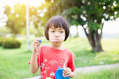 Portrait of happy girl holding plant on field