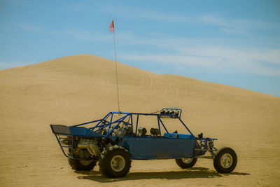 Off-road vehicle in desert against sky
