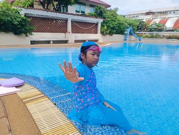 Portrait of young woman standing against swimming pool