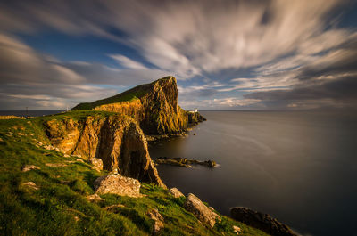 Scenic view of rocks by sea against sky