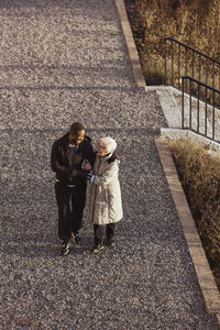 High angle view of male nurse walking with senior woman in park