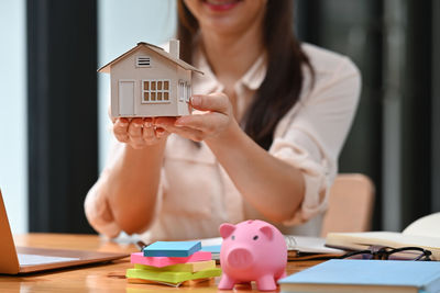 Midsection of woman holding smart phone on table