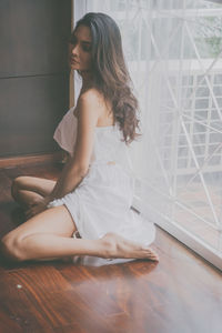 Young woman sitting on hardwood floor at home