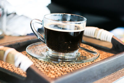 Close-up of cup of black coffee served in glass cup on tray