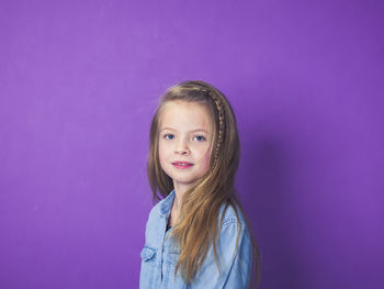 Portrait of smiling girl against purple background
