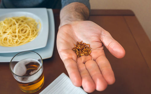 Cropped hand of man holding worms at restaurant