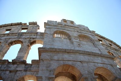 Low angle view of coliseum against clear blue sky