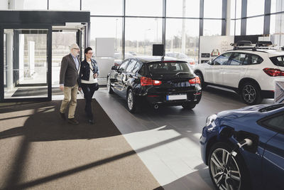 Senior man and woman entering in car showroom