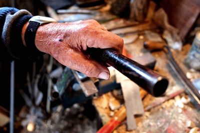 Cropped image of hand holding rod at workshop