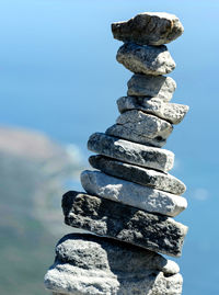 Stack of pebbles on rock by sea against sky