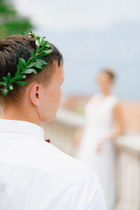 Rear view of man looking away wearing flowers