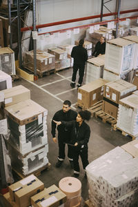 High angle view of male and female manual worker analyzing at distribution warehouse