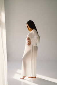 Portrait of young woman standing against curtain