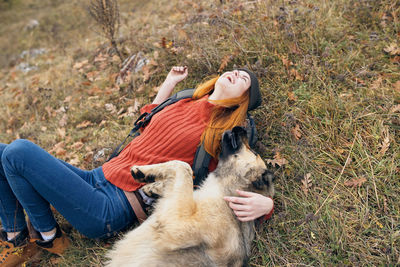 Woman with dog lying down on field