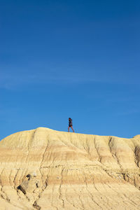 Man standing on land against blue sky