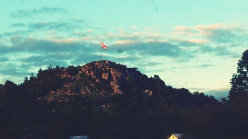 Low angle view of flag on rock against sky