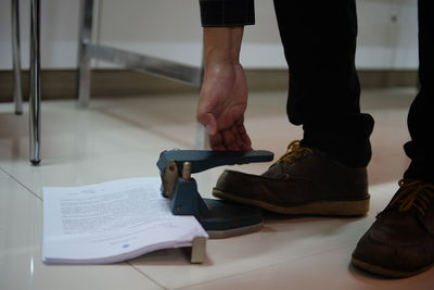 Low section of man punching papers on floor