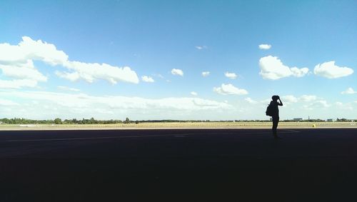 Silhouette of woman standing against cloudy sky