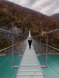 Rear view of man walking on footbridge