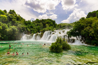 Scenic view of waterfall against cloudy sky