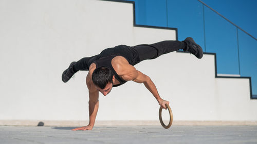 Full length of man exercising against wall