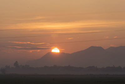 Scenic view of silhouette mountains against orange sky