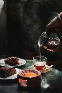 Cropped hand of woman pouring tea in cup