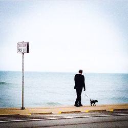 Rear view of man overlooking calm sea