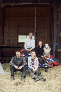 Siblings sitting with australian shepherd in barn