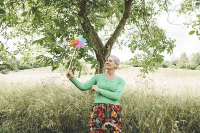 Rear view of woman with arms raised standing on field