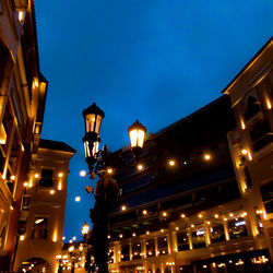 Low angle view of illuminated street light against buildings at night