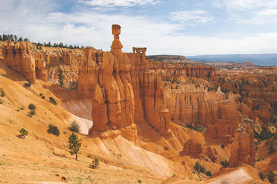 Rock formations on landscape against cloudy sky