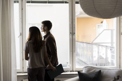 Multiracial couple looking through window while standing at new home