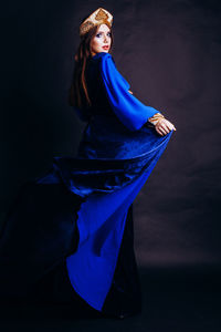 Portrait of beautiful woman in traditional clothing standing against black background