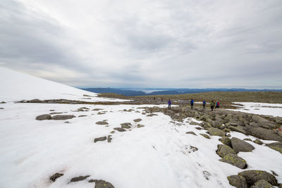 Hikers at rosendal alps against cloudy sky