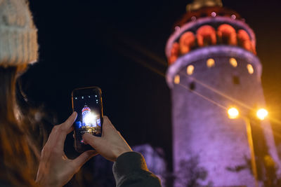 Man photographing illuminated smart phone at night