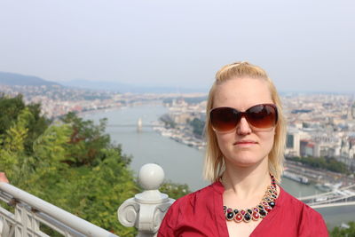 Close-up of mid adult woman standing by railing against cityscape