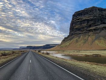 Road leading towards mountains against sky