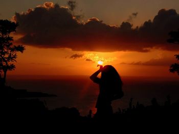 Silhouette of palm trees against sunset sky