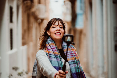 Woman holding monopod standing in alley