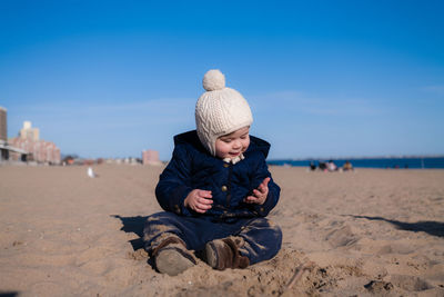 Extatic young boy is playing in the sand during in cold weather