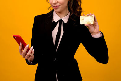 Midsection of a smiling young woman standing against orange background