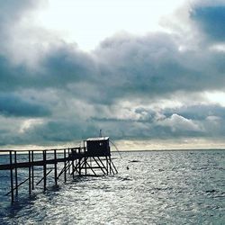 Pier on sea against cloudy sky