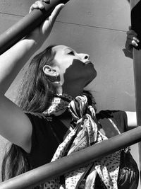 Low angle view of woman standing by metal against wall