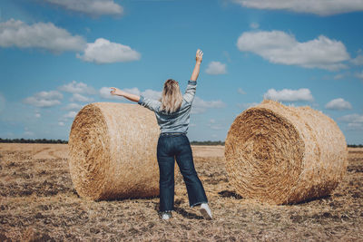 Full length of man with hay bales on field against sky