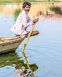 Side view portrait of fisherman sitting on boat in river