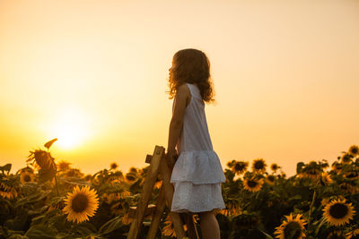 Woman standing on field against orange sky