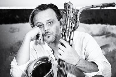 Portrait of bored man holding saxophone while sitting indoors